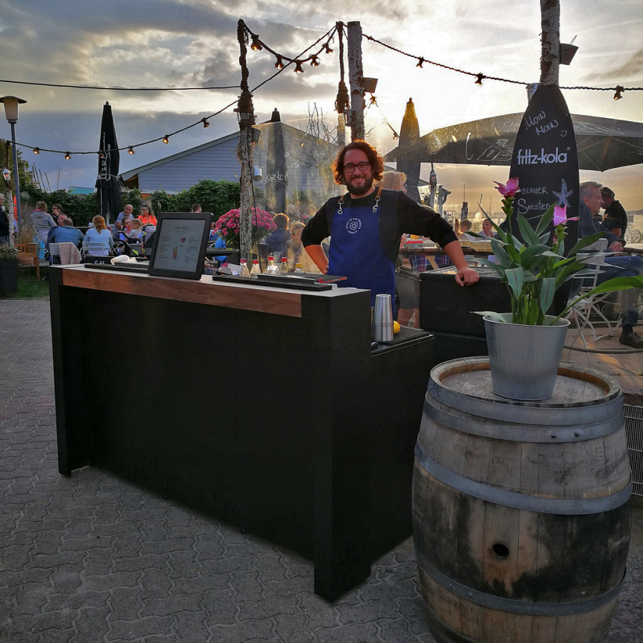 Schwarze Outdoor-Bar mit Bartop aus Holz.