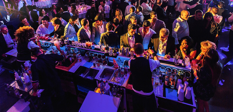 Cocktailbar inmitten einer Eventlocation mit vielen Personen.