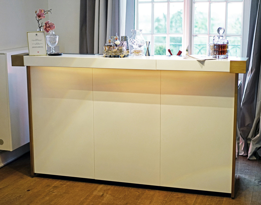 Mobile Theke in weiß mit edlen Seitenapplikationen aus brüniertem Messing.